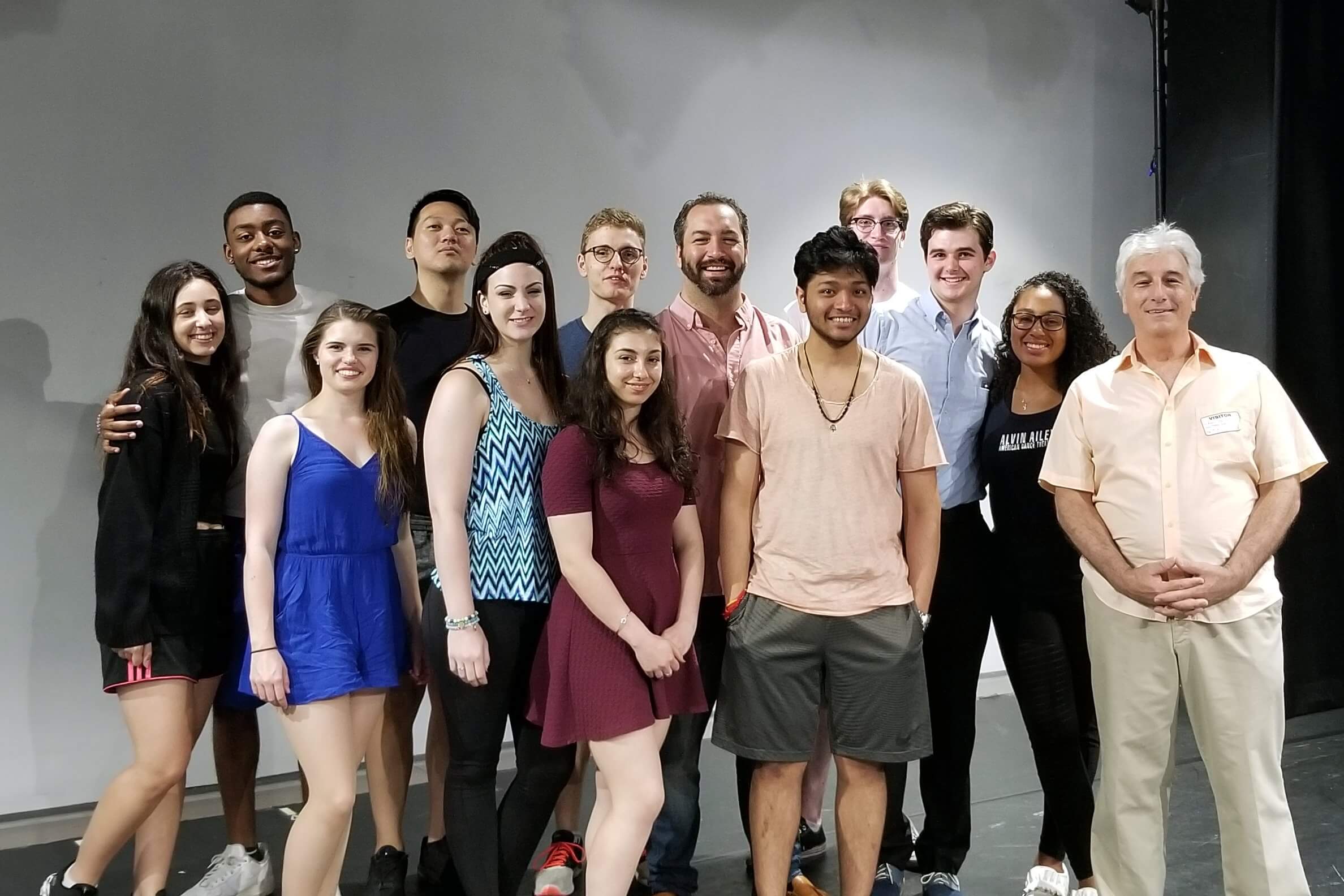Smiling diverse ensemble posing together on stage