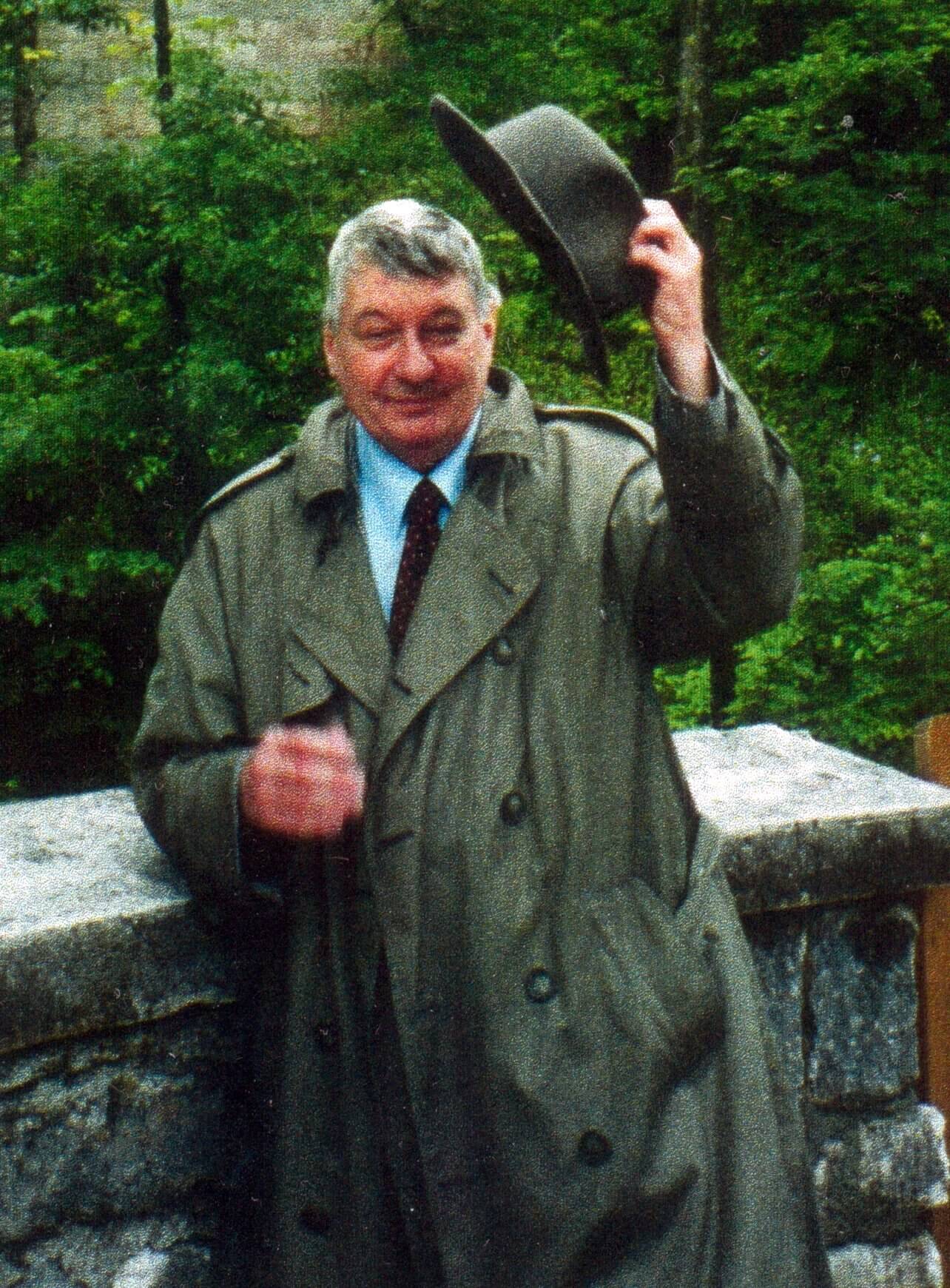 Man tipping hat in outdoor setting.