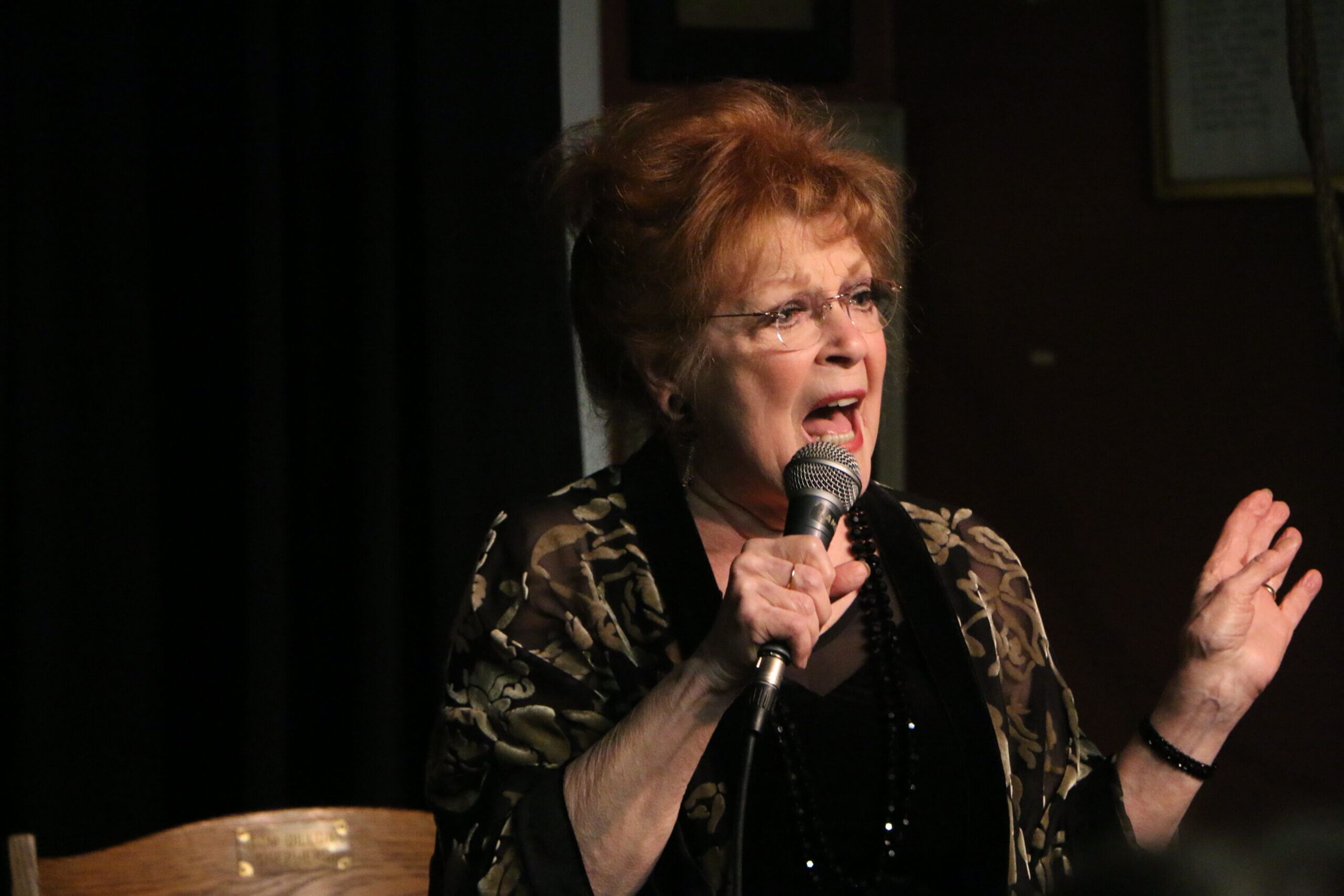 Woman singing passionately into a microphone.