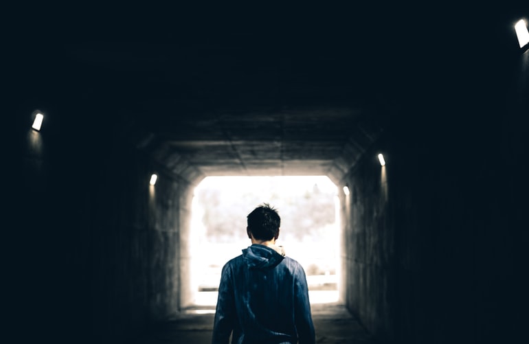 Person walking through dimly lit tunnel.