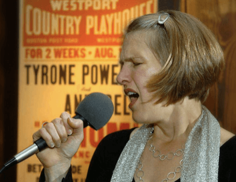 Woman passionately singing into microphone at venue